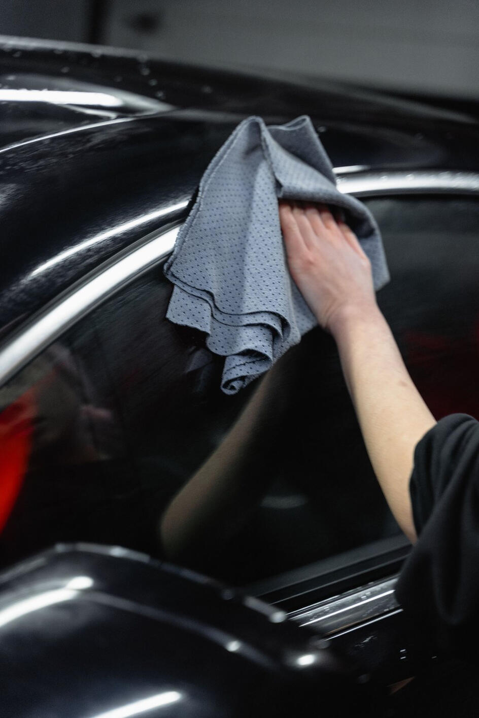 Professional auto detailing of a black vehicle with a microfiber towel